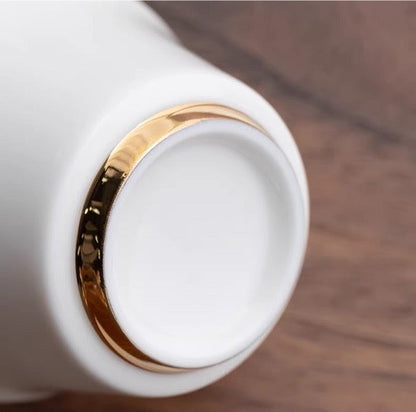 Close-up of "Lotus" Portable Tea Set's teapot with an elegant gold-rimmed design on wooden surface.