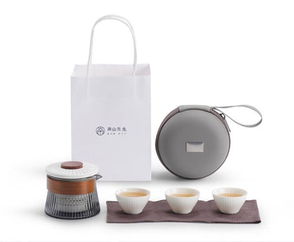 Portable "Mr. Nanshan" tea set with teapot, three cups, travel case, and bag. Ideal for tea brewing on the go.