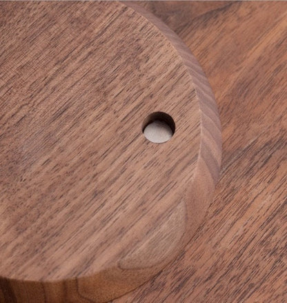 Close-up of a round wooden cutting board with a hole, showcasing its natural grain and texture.