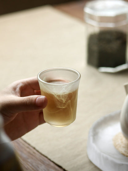 Hand holding "Ink Wash" Glass Tumbler filled with tea, showcasing elegant ink wash design and minimalist aesthetic.